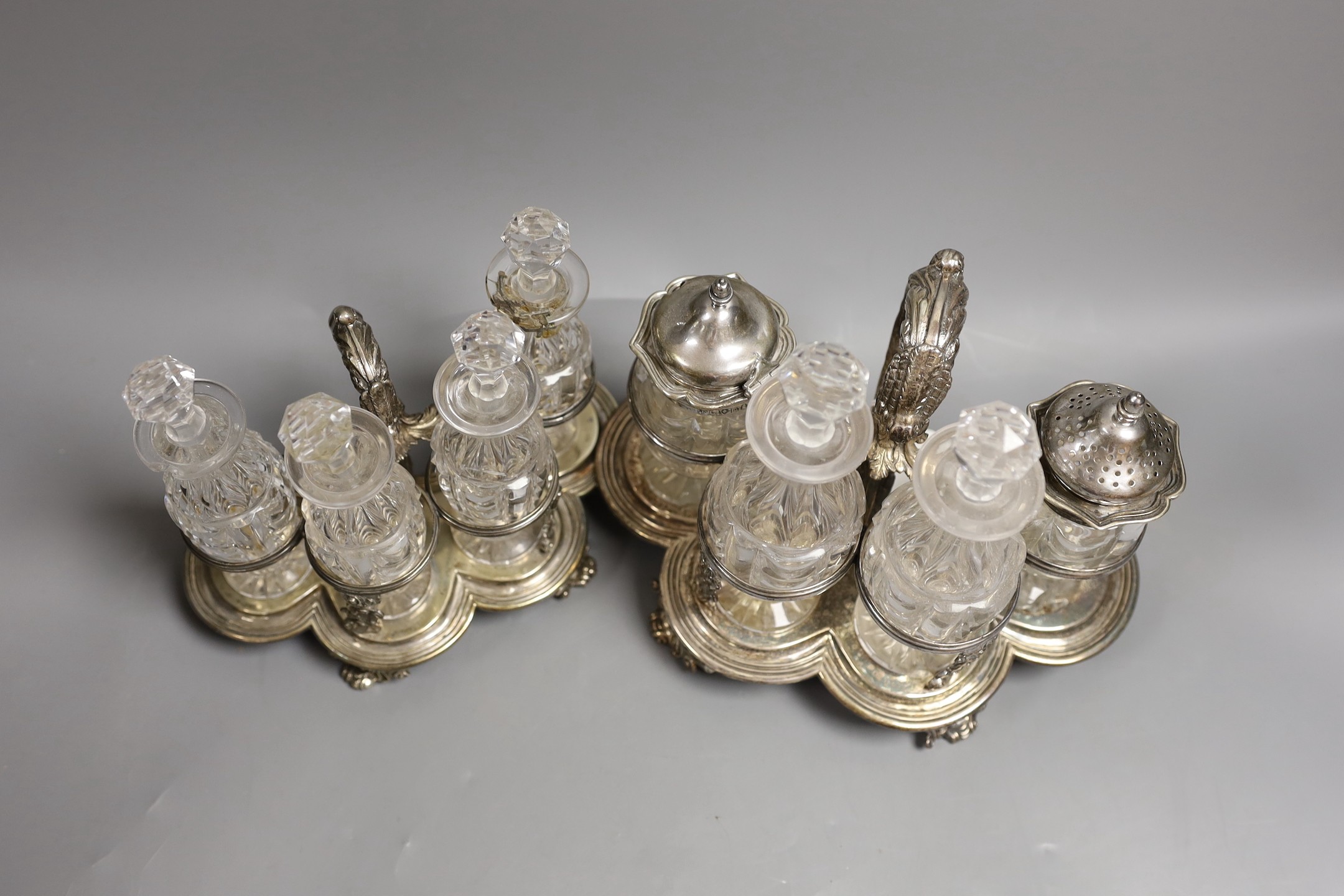 A graduated pair of William IV silver cruet stands, with ornate scroll handles, by John Fry II, London, 1830, both with four glass bottles, the largest with two silver mounted bottles, glass a.f., tallest 16cm, 34.3oz.